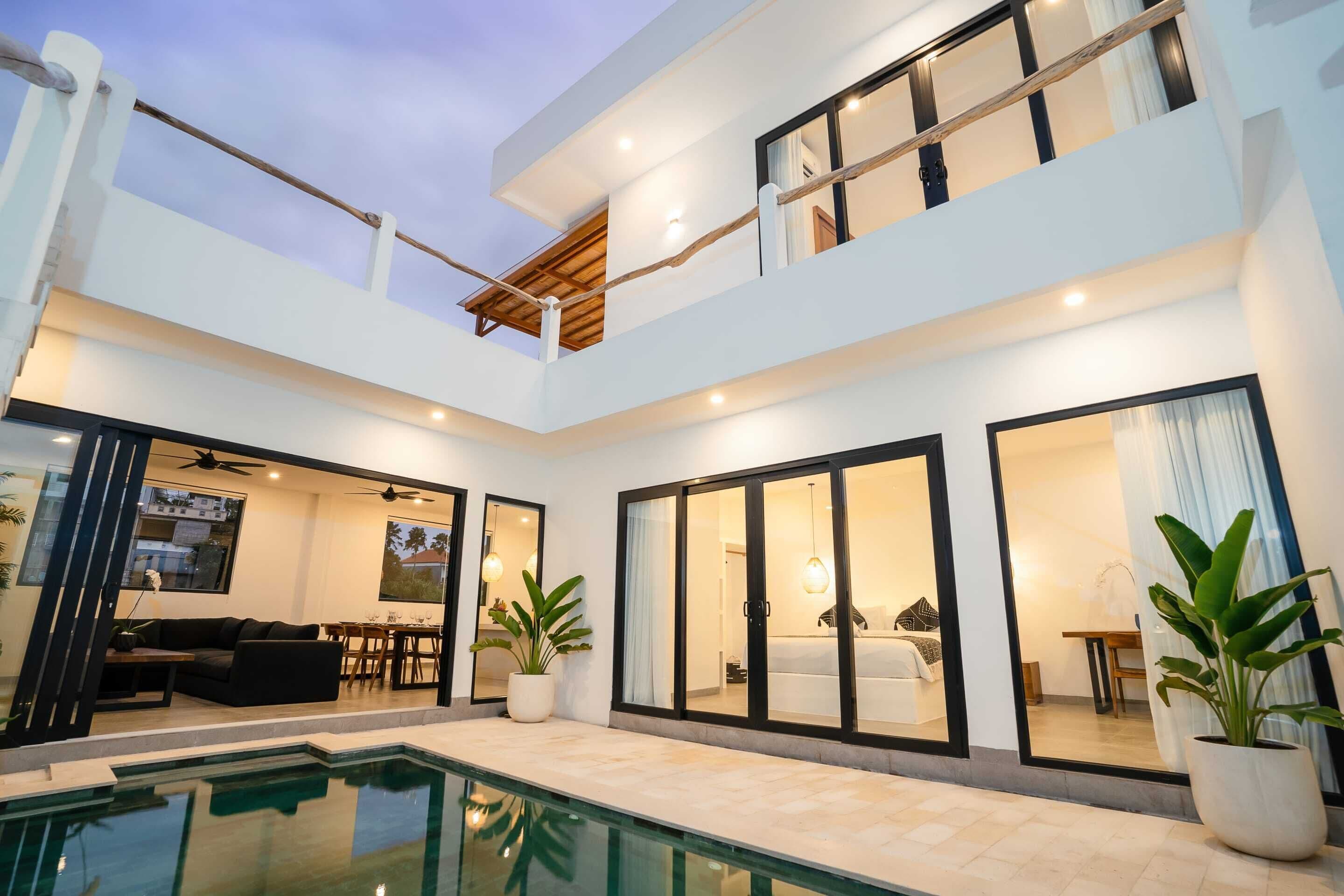 A modern two-story house with a swimming pool, large windows, and a dining area.