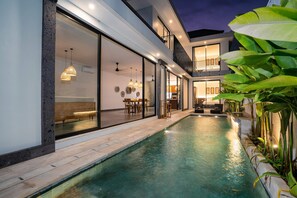 Una casa moderna con piscina, grandes puertas de cristal y un balcón.