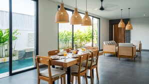 Un comedor con una mesa grande, sillas y lámparas colgantes.