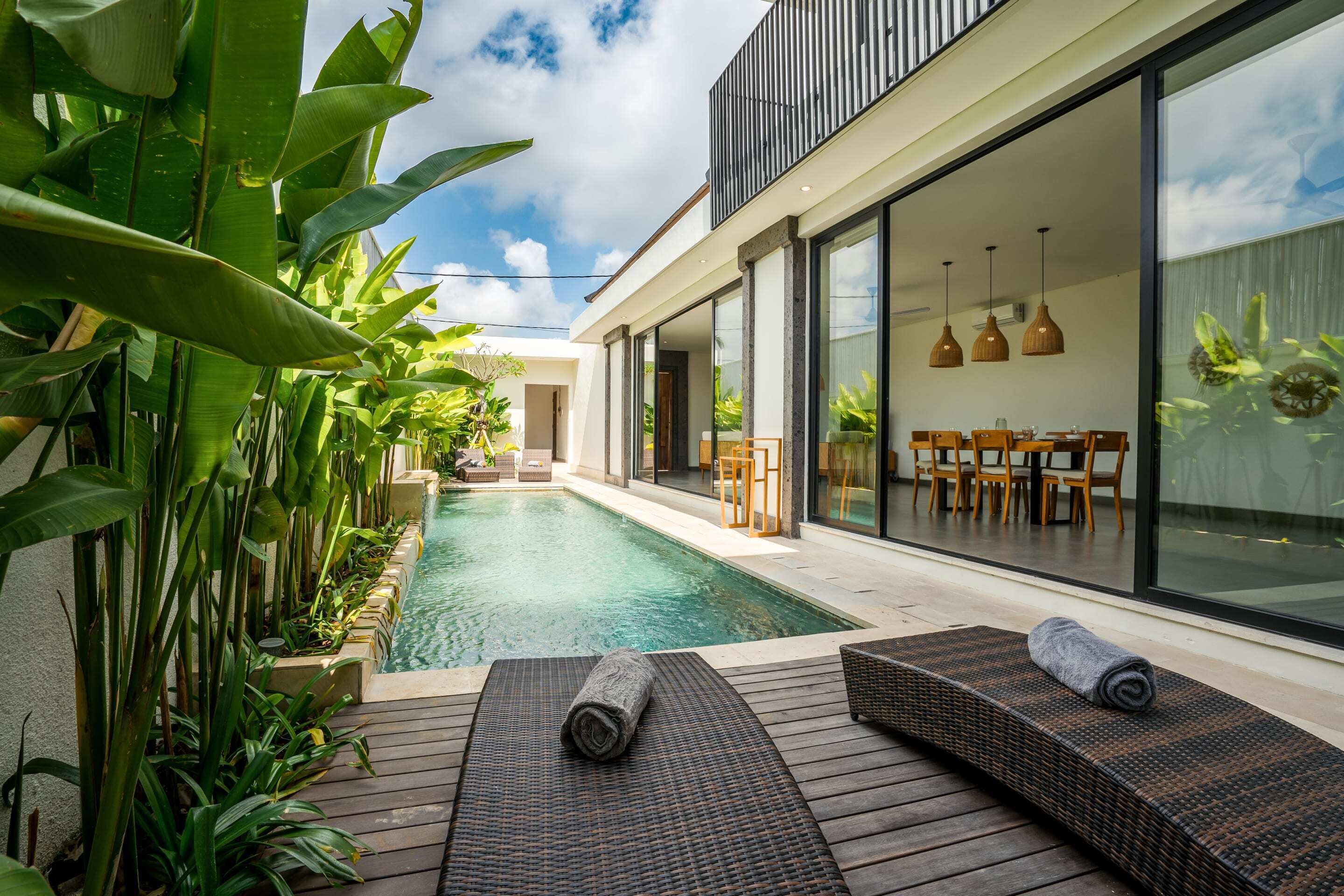 A modern house with a swimming pool, wooden deck, and outdoor furniture.