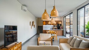 Una sala moderna con sofá, sillones, televisión y comedor.