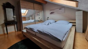 A bedroom with a large bed, a mirror, a nightstand, and a skylight. - Gemütliche Dachgeschosswohnung bei Tutzing am Starnberger See (Tutzing)