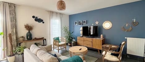 Un salon comprenant un canapé, des fauteuils, un téléviseur et un coin repas.