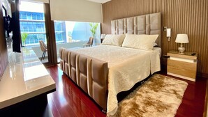 A modern bedroom with a large bed, a bedside table with a lamp, a view of the outdoors, and a wooden headboard. - "exclusive Apt Parque San Damián" (Santiago)