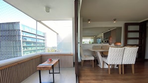 A modern dining area with a wooden table and chairs, large windows with a city view, and a wooden floor. - "exclusive Apt Parque San Damián" (Santiago)