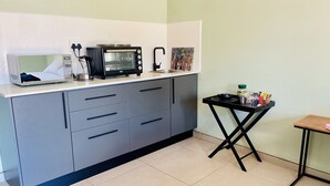Una kitchenette equipada con microondas, horno tostador y una pequeña mesa con utensilios de cocina.