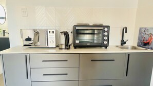 Una cocina moderna con horno integrado, hervidor y pileta.