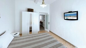 A bedroom with a bed, a wardrobe, a television, and a hallway leading to a bathroom. - La Goletta, terrace with a sea view (Portoferraio)