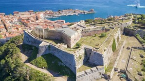 A coastal town with a prominent historic fortification, a marina, and a clear view of the sea. - La Goletta, terrace with a sea view (Portoferraio)