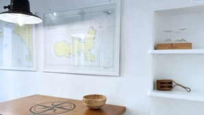 A wooden table with a compass design, a map on the wall, and a shelf with wine glasses and a wooden box. - La Goletta, terrace with a sea view (Portoferraio)