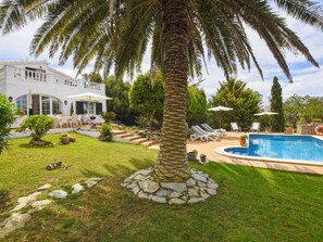 A modern house with a pool, surrounded by a well-maintained lawn and palm trees. - Tortolas by Interhome (Menorca/Alaior)