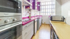 Uma cozinha compacta com forno embutido, micro-ondas e torradeira. Possui uma pia, bancada de madeira e uma janela com vista.