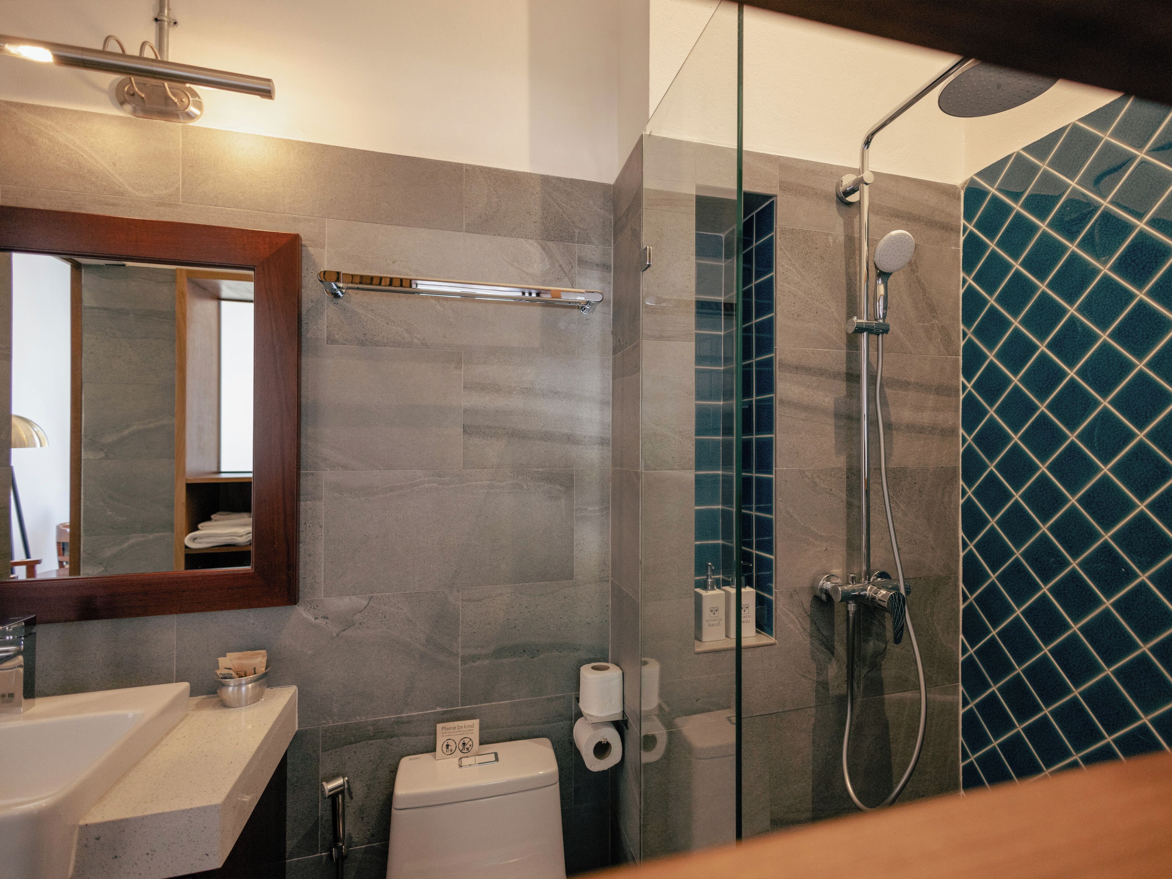 Een moderne badkamer met een glazen douchecabine, een toilet en een wastafel.