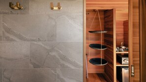 A bathroom with stone tiles, a wooden door, and a shelf with a hanging basket. - Pha Nya Residence (Luang Prabang)