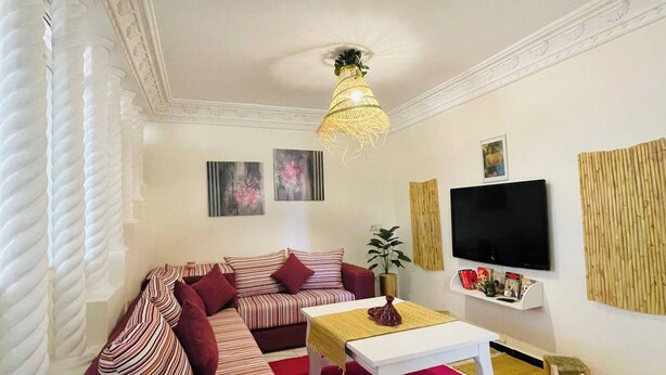 A living room with a sofa, a coffee table, a TV, and decorative items. - Coquet Appartement À Casablanca (Casablanca)