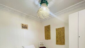 A bedroom with a bed, a nightstand, a wardrobe, and a hanging light fixture. - Coquet Appartement À Casablanca (Casablanca)
