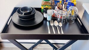 Una mesa de comedor con platos negros, cubiertos, un tarro de sal, una botella de aceite y diferentes aperitivos.