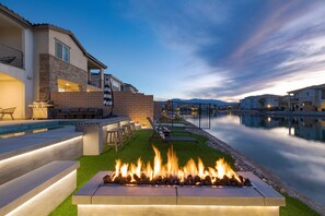 A modern outdoor patio with a fire feature, pool, and lounge area. - Lakefront w/ Private Pool, Great for Festival Season | Lago Luxe by AvantStay (Indio)