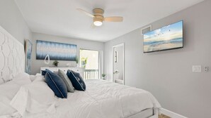 A bedroom with a bed, a ceiling fan, a TV, and artwork on the walls. - Beach Rd, 300ft to Beach Access & 500ft to Siesta Key Village, 2bdr (Siesta Key)