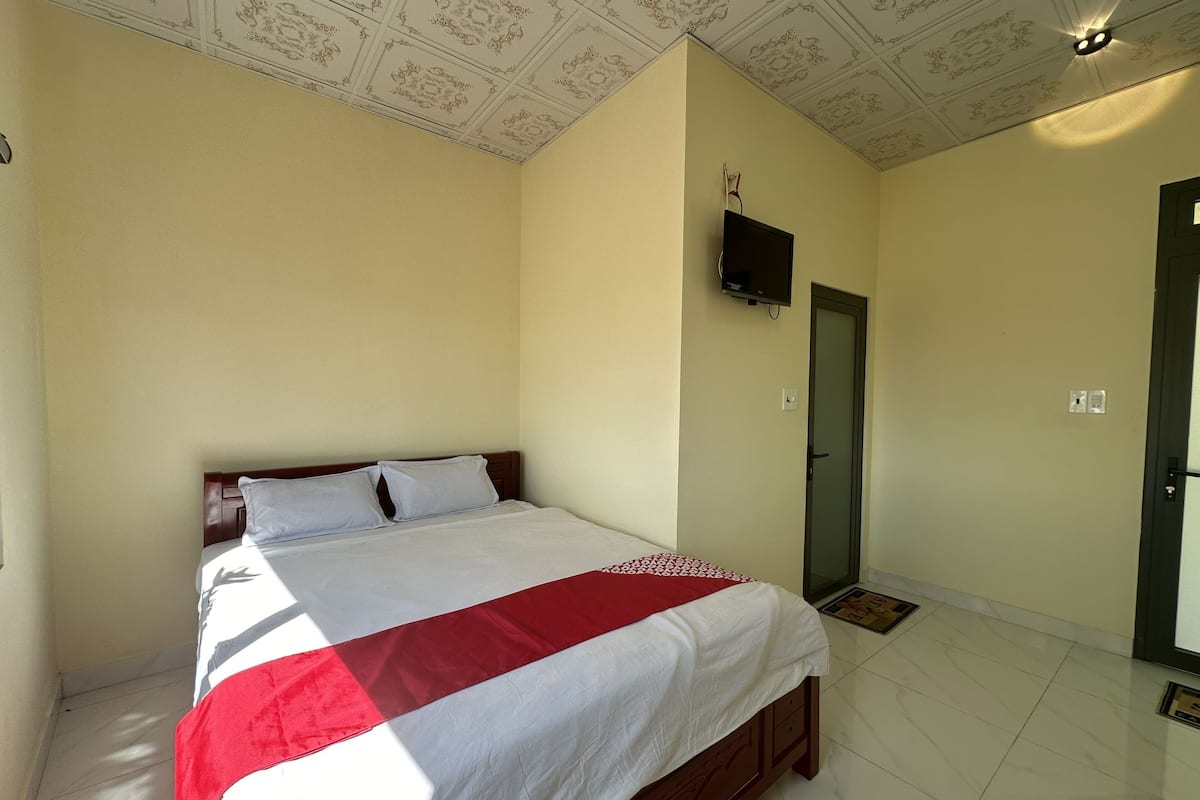 A bedroom with a bed, a television mounted on the wall, and a door.