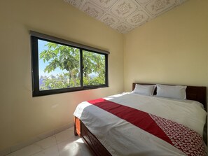 A bedroom with a large window, a bed with white and red bedding, and a wooden headboard. - OYO 1228 Gia Hoang Homestay (Da Lat)