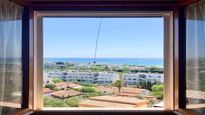 A view from a window with a clear sky, overlooking a coastal area with buildings and greenery. - The Blue Panoramic Penthouse (Porto Cesareo)