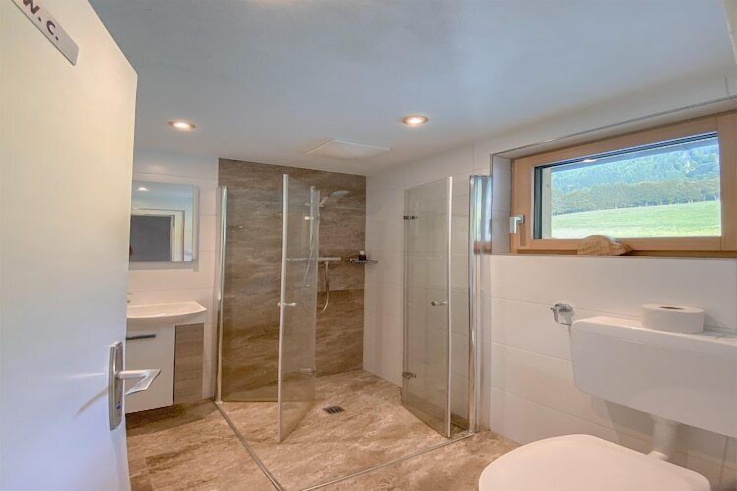 Een moderne badkamer met een douchecabine van glas, een toilet en een wastafel.