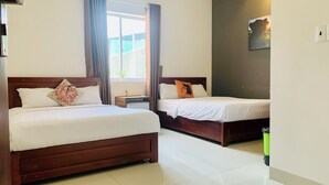 A hotel room with two beds, a small table, and a window with curtains. - talofofo hotel (Da Nang)