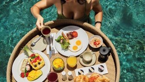 A person in a swimsuit holding a tray with breakfast items including eggs, toast, and fruit. - talofofo hotel (Da Nang)
