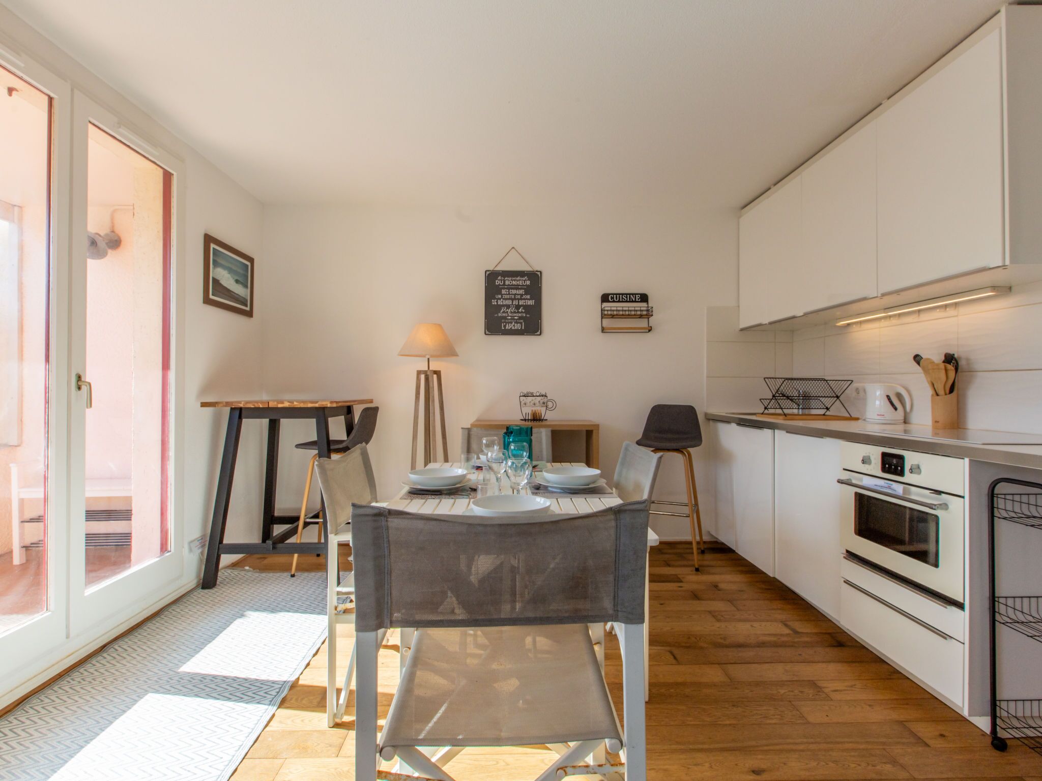 Une cuisine moderne avec des meubles blancs, une table à manger avec des chaises et un petit coin repas.