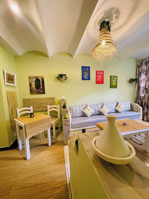 A living room with a sofa, chairs, a table, and a hanging light fixture.