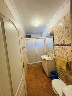 A bathroom with a toilet, sink, and mirror.