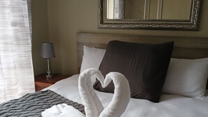 Quarto de hotel com uma cama, um espelho grande e uma mesa de cabeceira com abajur.