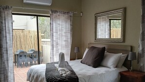 Quarto com cama, mesa de cabeceira, abajur e vista para o exterior.