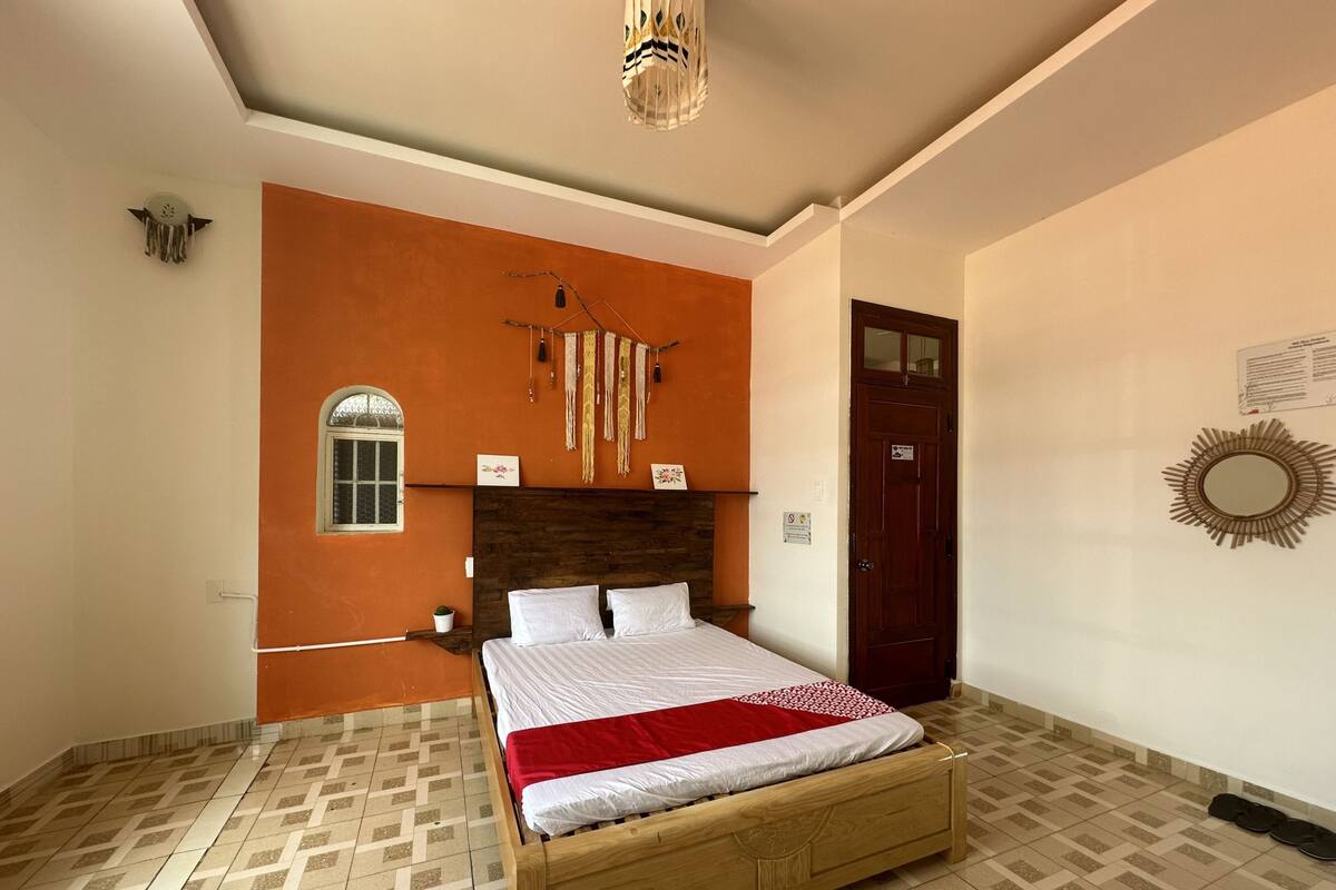 A bedroom with a wooden bed, a small window, a door, and a decorative wall hanging.