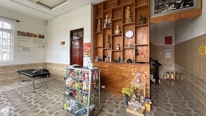 A lobby with a reception desk, a glass display case with snacks, a wooden shelf with decorative items, and a clock on the wall. - SPOT ON 1229 Happy Dream Homestay (Lam Vien - Da Lat)