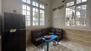 A room with a black refrigerator, a brown leather sofa, a blue table, and large windows. - SPOT ON 1229 Happy Dream Homestay (Lam Vien - Da Lat)