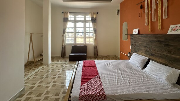 A hotel room with a bed, a window with curtains, a wooden headboard, and a wall with hanging decorations. - SPOT ON 1229 Happy Dream Homestay (Lam Vien - Da Lat)