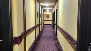 A hotel corridor with patterned carpet, wooden trim, and doors on both sides. - Georgian Paradise (Kutaisi)