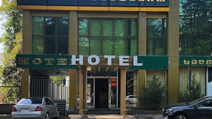 A modern hotel with a prominent "HOTEL" sign above the entrance, large windows, and a parking area with cars. - Georgian Paradise (Kutaisi)
