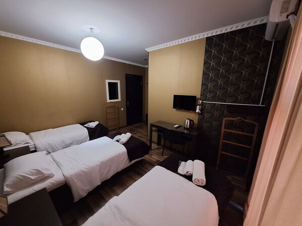 A hotel room with two beds, a desk, a television, and a mirror.