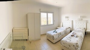 A bedroom with two beds, a wardrobe, a window, and a bedside table with a lamp. - New Orange Villa 6-BR A/C with a Salted Heated Pool & BBQ, Great Mountain View (Cagnes-sur-Mer)