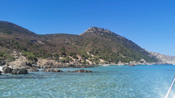 A coastal landscape with clear turquoise waters, rocky shores, and a mountainous backdrop. - Charmante Maison Avec Piscine et Pétanque (Lumio)