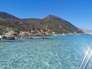A coastal landscape with clear turquoise waters, rocky shores, and a mountainous backdrop. - Charmante Maison Avec Piscine et Pétanque (Lumio)