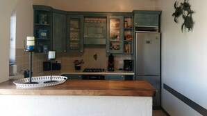 A kitchen with teal cabinets, a wooden countertop, and a stainless steel refrigerator. - Charmante Maison Avec Piscine et Pétanque (Lumio)