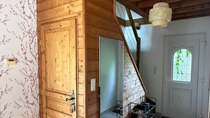 Ein Holzinnenraum mit Treppe, einer Tür und einem Schuhregal.
