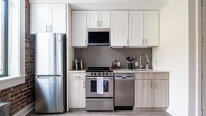 Una cocina moderna con armarios blancos, electrodomésticos de acero inoxidable y una pared decorativa de ladrillo.