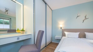 A hotel room with a bed, a desk, a chair, a window, and a wall-mounted light fixture. - Hier Lautet das Motto: Wohnen und Entspannen mit Heimat-atmosphäre (Westerland)