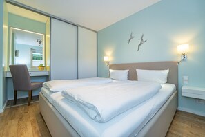 Relax in a serene space with a large bed, desk, and window view of lush greenery.