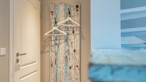 A hallway with a wooden wall art piece featuring three white hangers and a door with a modern handle. - Hier Lautet das Motto: Wohnen und Entspannen mit Heimat-atmosphäre (Westerland)